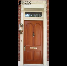 A mahogany door with arched raised panels and moldings.