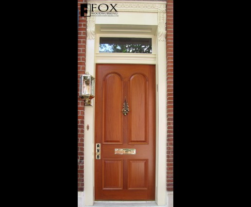 A mahogany door with arched raised panels and moldings.