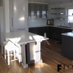 A view of the island, refrigerator, and base cabinets, and white glass backsplash in Strathmere, NJ.