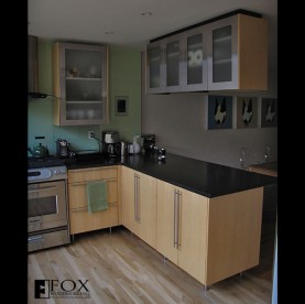 A view of the tiger maple base cabinets, stainless steel doors above, and honed black granite top.