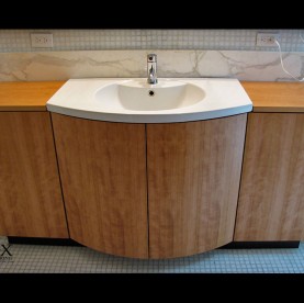 A quarter sawn cherry veneer vanity cabinet with curved doors.