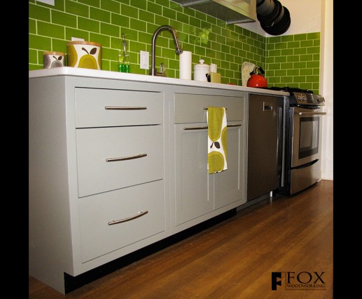 Green painted base cabinets with green glass tile backsplash.