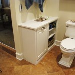 This painted wall shelf is around the corner from a tilt out hamper that is behind the paneled door.