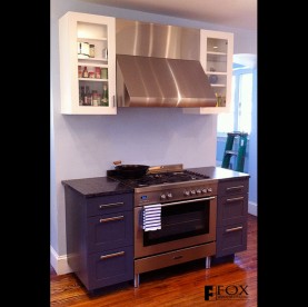 Painted cabinetry surrounds the range and range hood.