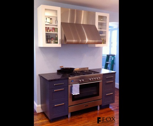 Painted cabinetry surrounds the range and range hood.