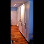 Next to the range cabinets, there are pantry cabinets with glass display doors.