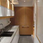 The white painted galley kitchen drawer fronts can be seen in this view of the wall cabinets and paneled refrigerator.