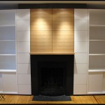 A rift sawn white oak entertainment center has a mantlepiece and flanking white painted cabinets.