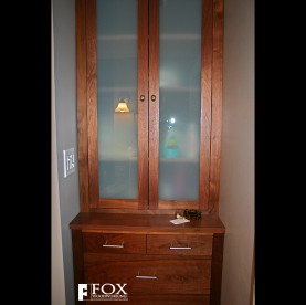 A solid walnut linen cabinet with frosted glass panels.