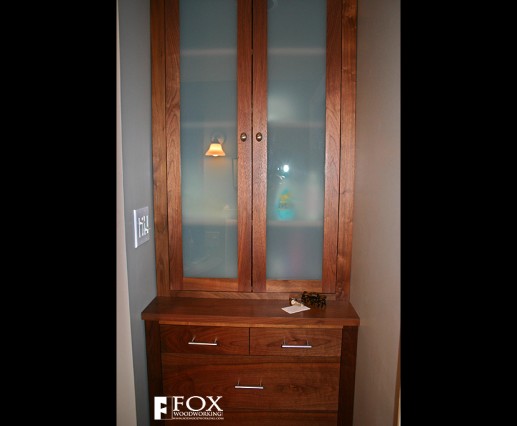 A solid walnut linen cabinet with frosted glass panels.